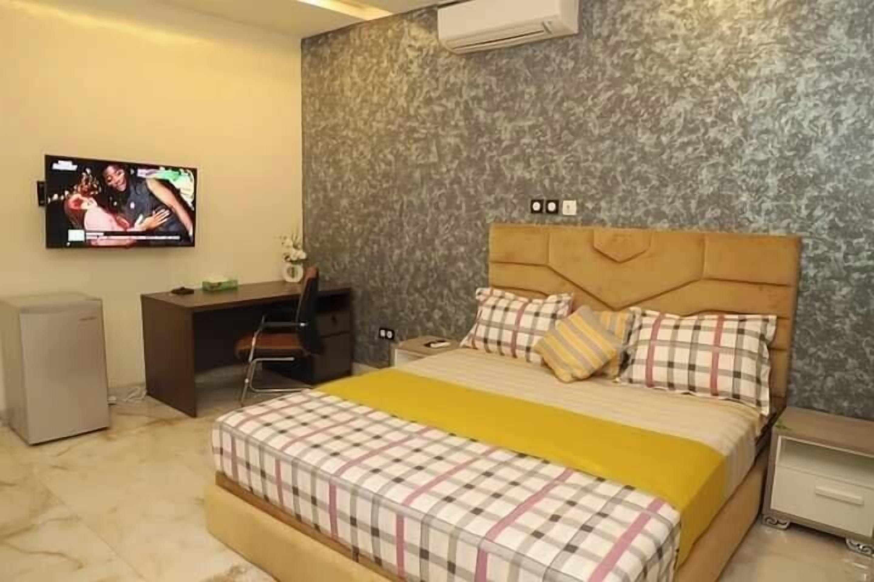 A bedroom with a bed, a desk, a chair, and a television.