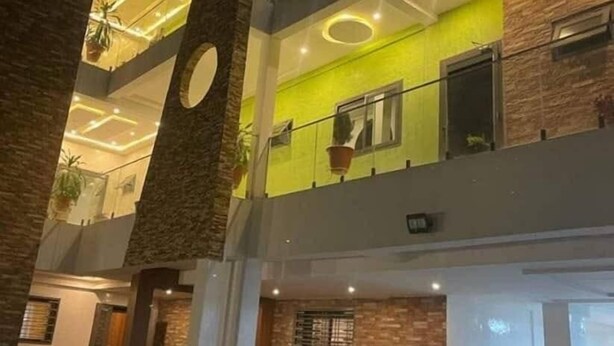 Un interior de varios niveles con un diseño moderno, que presenta un atrio central con una escalera, múltiples pisos y una combinación de elementos de ladrillo y vidrio.