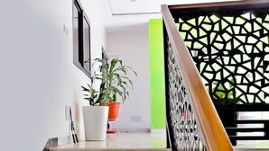 Una escalera de mármol con barandilla de madera y una balaustrada negra geométrica.