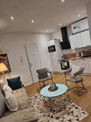 Una sala de estar moderna con un sofá, dos sillones, una mesita de centro y una alfombra estampada.