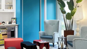 A modern lounge area with seating, a coffee machine, and a large window. - B&B Hotel Saint-maur Créteil (Saint-Maur-des-Fosses)