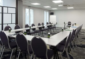 A conference room with long tables, chairs, a whiteboard, and a projector screen. - B&B Hotel Saint-maur Créteil (Saint-Maur-des-Fosses)