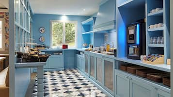 A modern kitchen with blue cabinetry, a checkered floor, and a coffee machine.