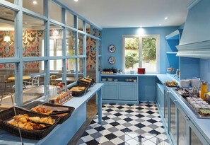 A breakfast buffet with various food items, a checkered floor, and a window with a view of greenery. - B&B Hotel Saint-maur Créteil (Saint-Maur-des-Fosses)