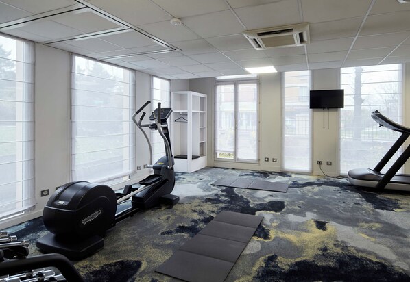 Un gimnasio con cintas de correr, una bicicleta estática y una máquina de pesas.
