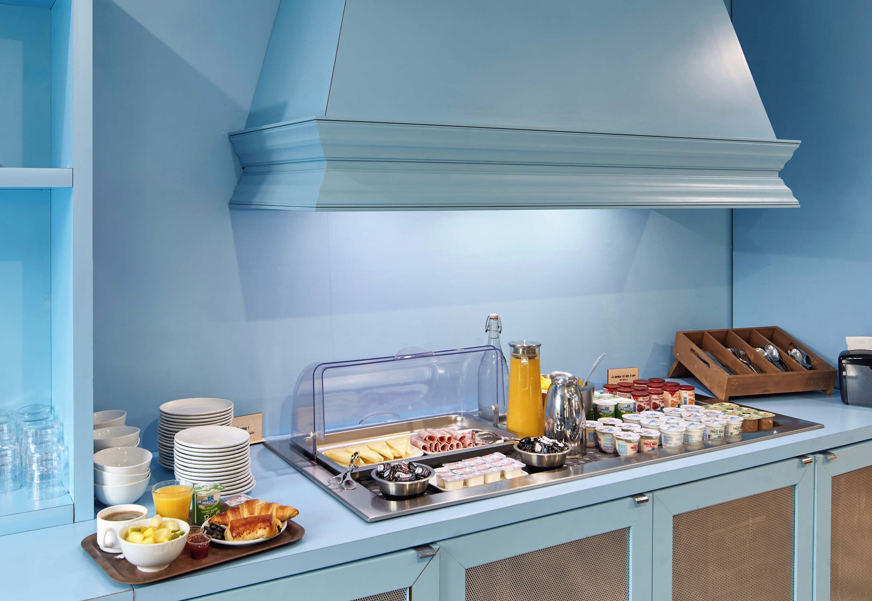 Een ontbijtbuffet met diverse gerechten, een koffiehoek en een sapautomaat.
