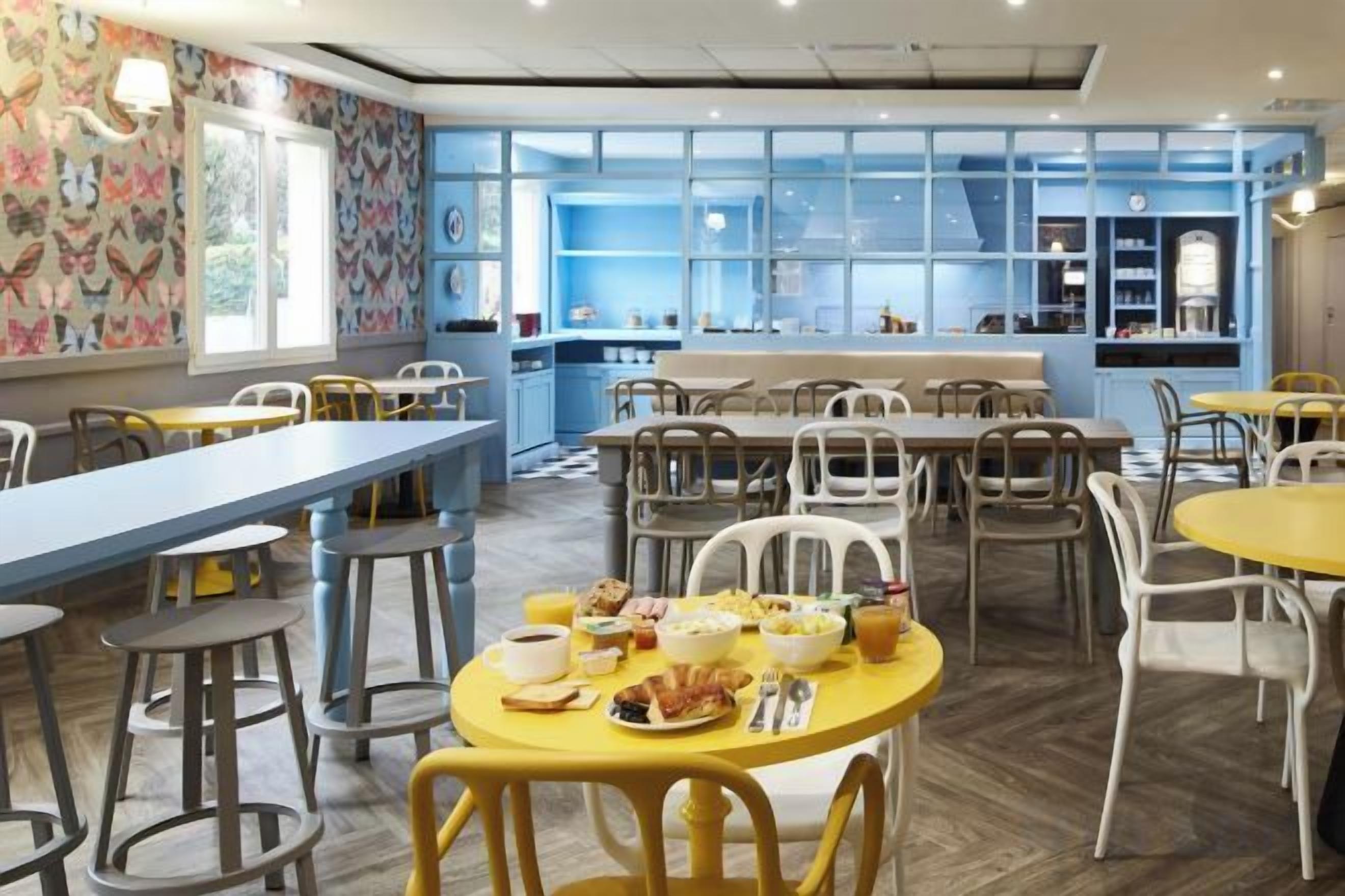 A restaurant with high tables and chairs, a counter, and a view through large windows.