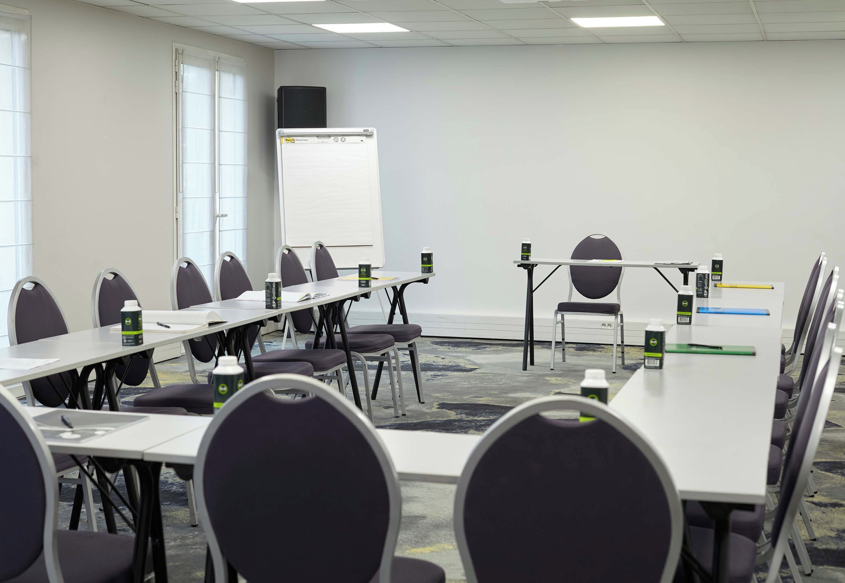 A conference room with a whiteboard, tables, chairs, and a projector.