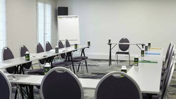 A conference room with a whiteboard, tables, chairs, and a projector.