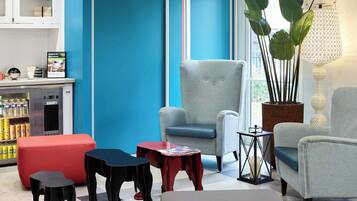A modern lounge area with seating, a coffee machine, and a large window.