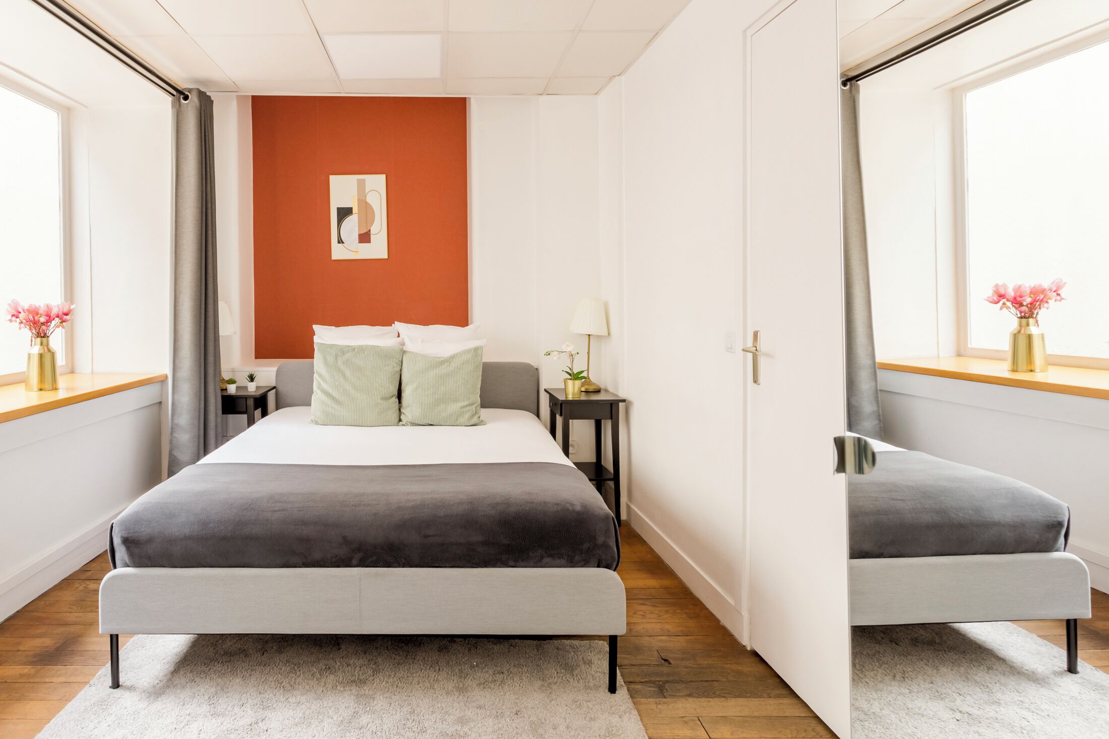 A bedroom with a bed, a nightstand, a lamp, and a window with curtains.