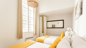 Une chambre d’hôtel avec deux lits, une grande fenêtre, un mur en briques et un miroir.