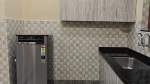 Una cocina compacta con un refrigerador de acero inoxidable, una encimera negra y un lavamanos.