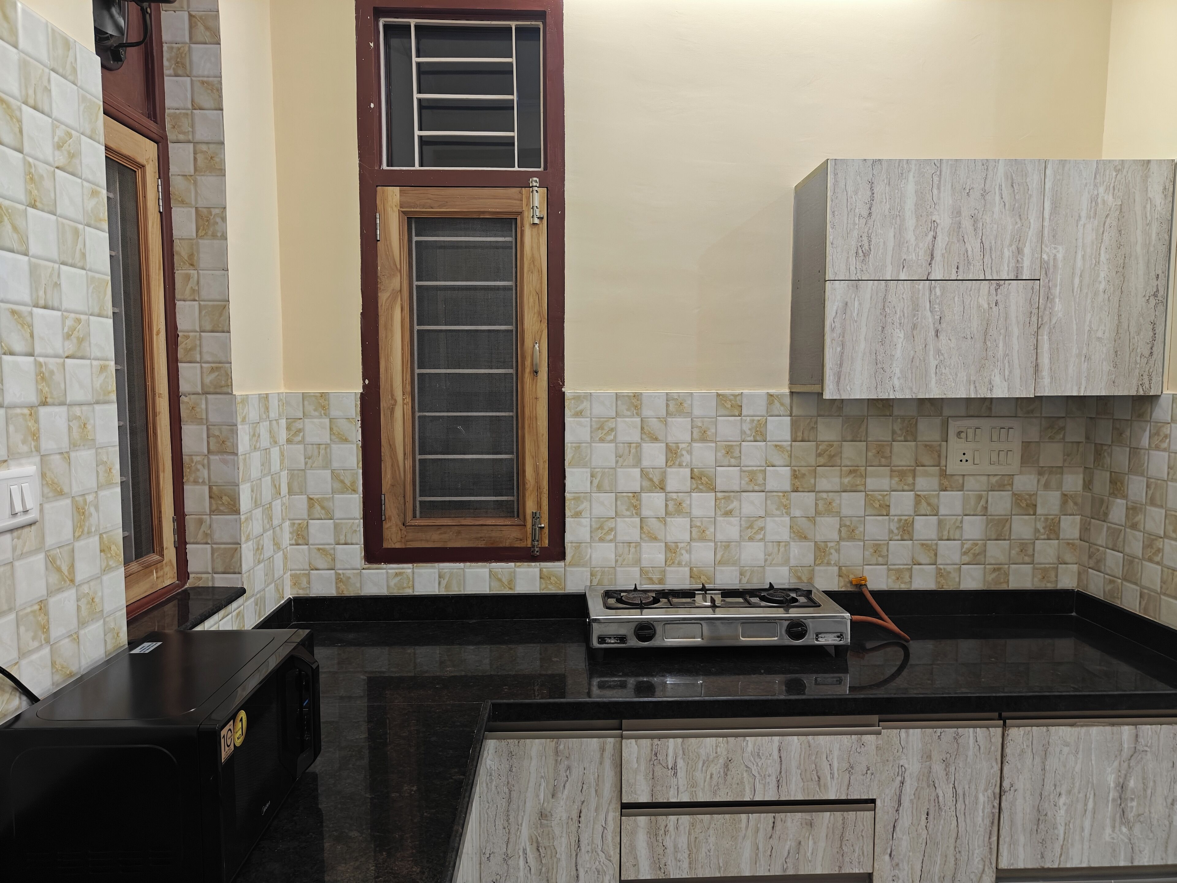 A kitchen with a gas stove, a microwave, and a cabinet.