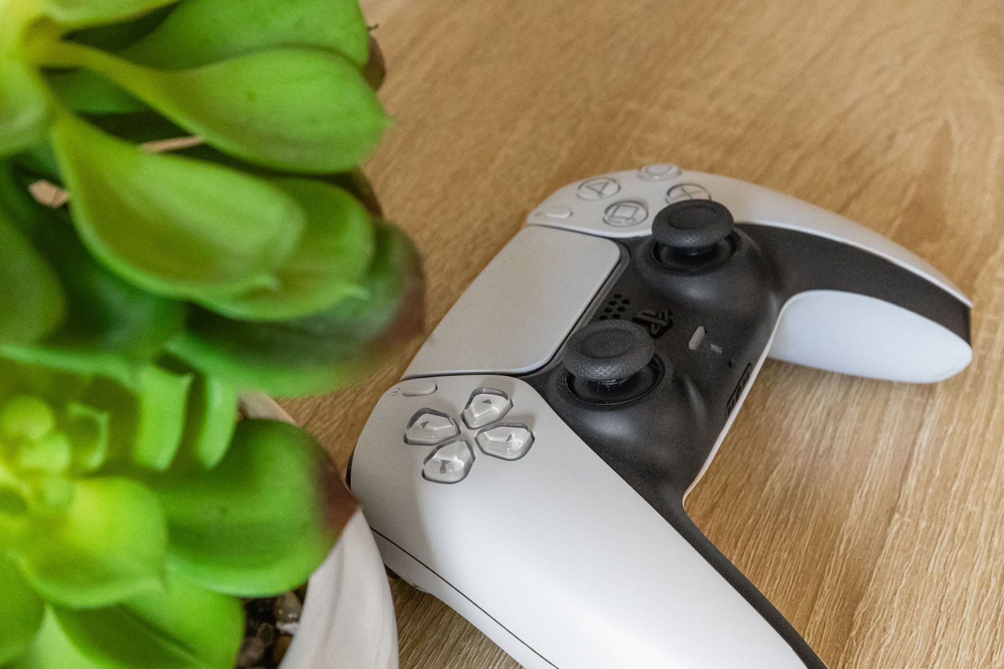 A PlayStation controller on a wooden surface.