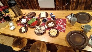 Ett matbord i trä med olika rätter, inklusive bröd, ost och grönsaker, upplagt på en röd servett.