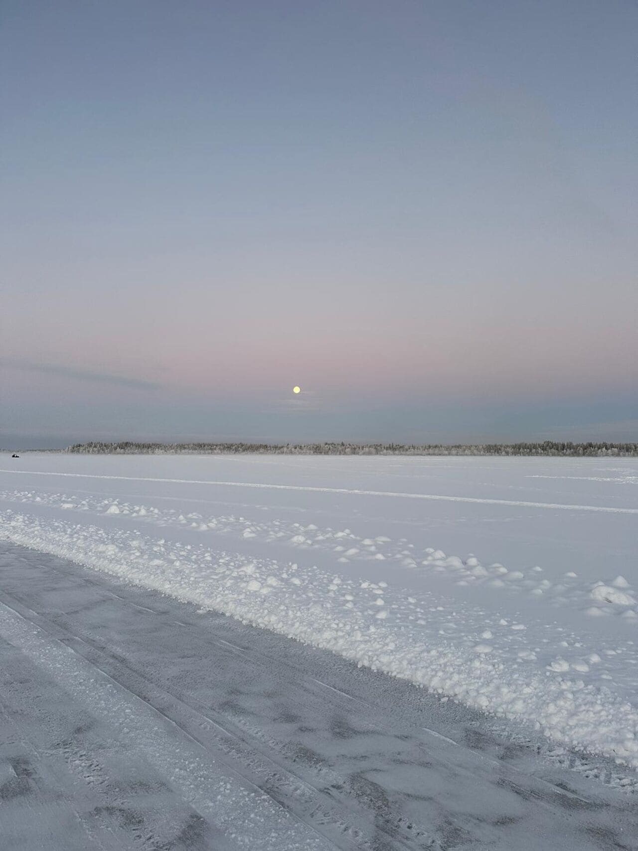 A frozen landscape with a clear sky and a visible moon.