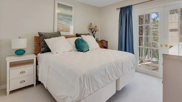 A bedroom with a bed, nightstand, lamp, and a view through a glass door.