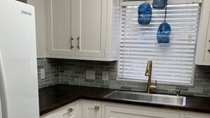 A kitchen with white cabinets, a stainless steel sink, and a Samsung refrigerator.