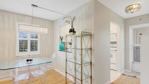 A modern kitchen with white cabinets, a glass dining table, and a metal shelving unit.