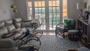 A living room with a sofa, chairs, a patterned rug, and a view through a sliding glass door.