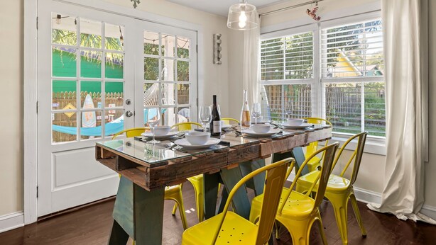 A dining area with a wooden table set for four, yellow chairs, and a hanging light fixture.
