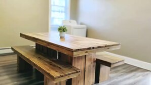 A wooden dining table with benches in a room with light-colored walls and a window. - Spacious Urban Townhouse • Groups and Family (Hartford)