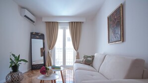 A living room with a beige sofa, a round coffee table, a potted plant, a mirror, and a painting on the wall. - Captain's Villa (Budva)