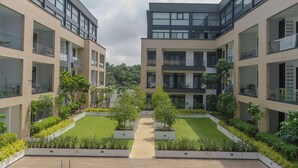 A modern building with multiple balconies, a central courtyard with greenery, and a clear sky. - RoyalRest at Embassy Gardens (Accra)