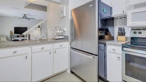Une cuisine moderne avec des armoires blanches, un réfrigérateur en acier inoxydable, un four à micro-ondes et un four traditionnel.