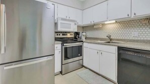 Une cuisine moderne dotée d’appareils électroménagers en acier inoxydable, de meubles blancs, d’un four à micro-ondes, d’une cuisinière et d’un lave-vaisselle.