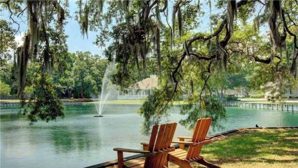 Un cadre paisible au bord du lac, avec des chaises en bois et une fontaine.