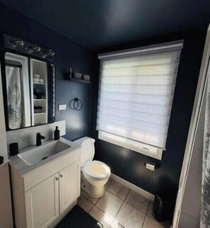 Une petite salle de bain avec des toilettes, un lavabo et une fenêtre.