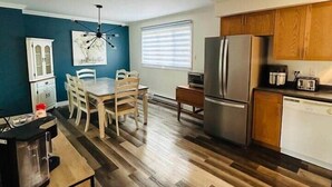 Una cocina moderna con armarios de madera, un refrigerador de acero inoxidable y un comedor con mesa y sillas de madera.