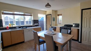 A compact kitchen with a wooden table and chairs, a microwave, and a dishwasher. - Sizeable 4 bed property on Huntingdon Ring road (Huntingdon)