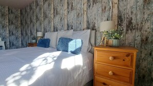 A bedroom with a bed, wooden nightstand, dresser, and a mirror. - Sizeable 4 bed property on Huntingdon Ring road (Huntingdon)