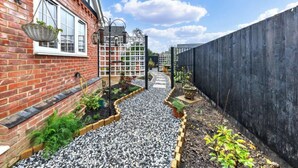 A narrow pathway flanked by a brick wall and a wooden fence, leading to a gate. - Sizeable 4 bed property on Huntingdon Ring road (Huntingdon)
