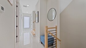 Ein Flur mit einer Holztreppe, einer blauen Bank und einem Spiegel an der Wand.
