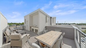 Eine Terrass mit Essbereich, Sitzgelegenheiten und einem Grill.