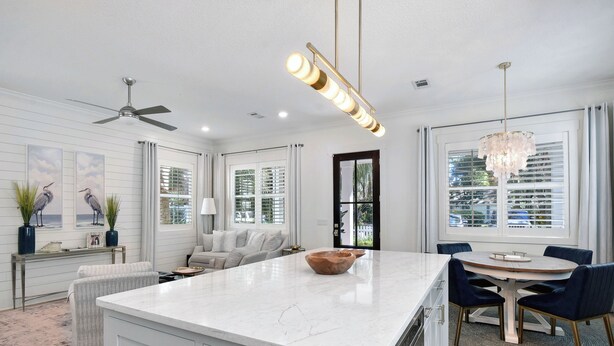 A spacious kitchen with a large island, a dining area with a round table, and a ceiling fan. - 3 bedroom/3.5 bath house.  Master on the main!  South end. (Saint Simons Island)