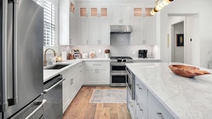 A modern kitchen with white cabinetry, stainless steel appliances, and a marble countertop. - 3 bedroom/3.5 bath house.  Master on the main!  South end. (Saint Simons Island)