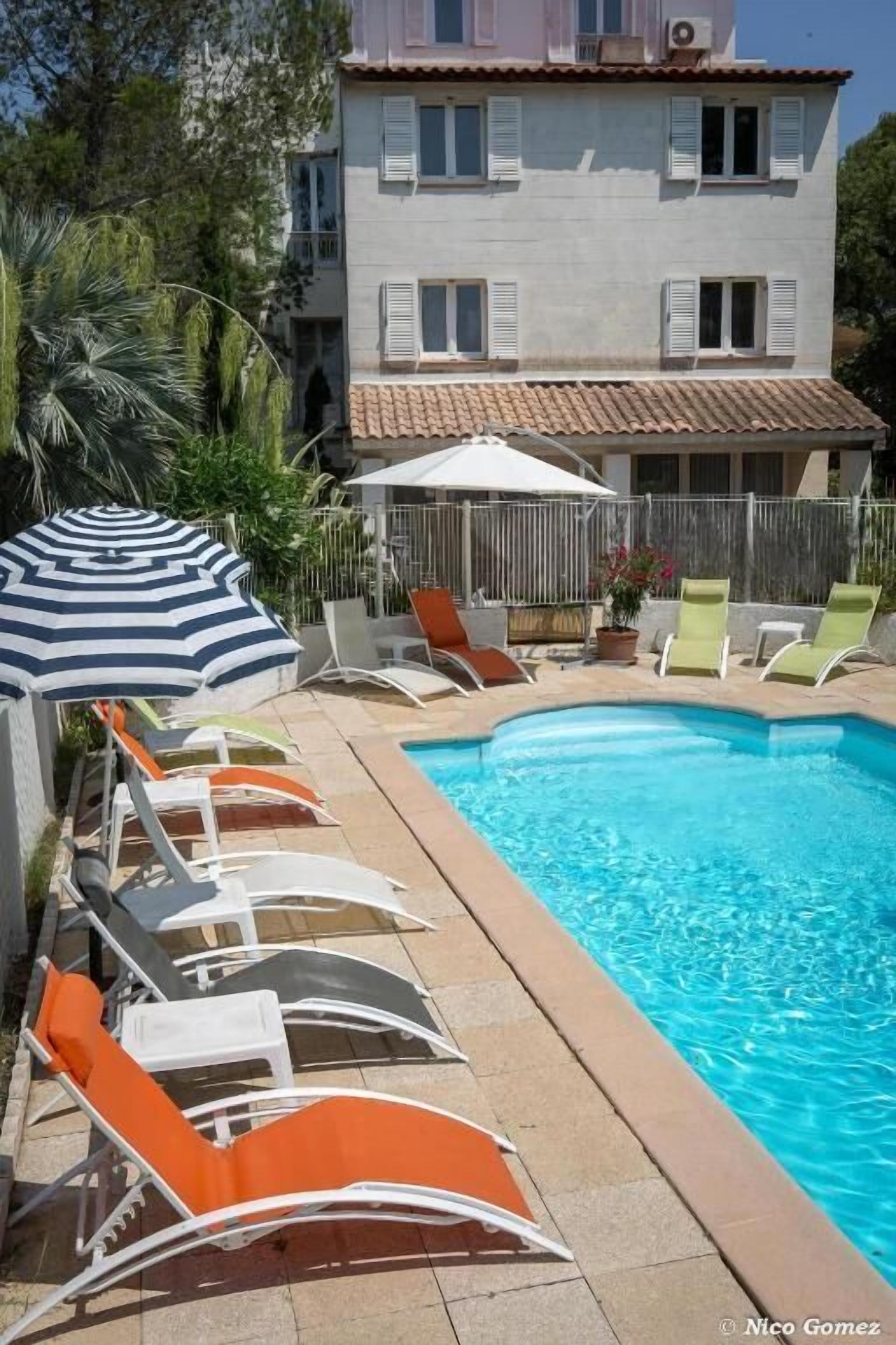 Una piscina al aire libre de temporada, sombrillas, tumbonas