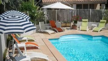 Una piscina al aire libre de temporada, sombrillas, tumbonas