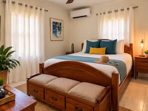 A bedroom with a wooden bed, a bedside table, a lamp, a potted plant, and a window with curtains. - Bay View Island Escape 3BR + Generator + A/C (St. Thomas)