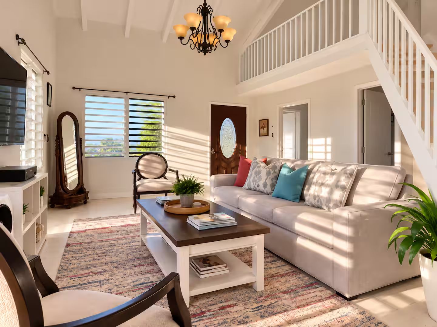A spacious living room with a white sofa, a coffee table, and a large mirror.