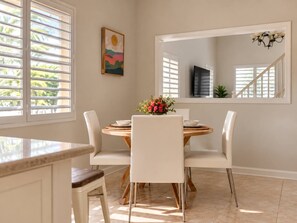 A dining area with a round table, white chairs, and a vase of flowers. - Bay View Island Escape 3BR + Generator + A/C (St. Thomas)