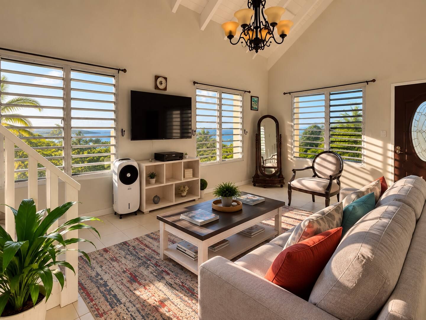 A spacious living room with a large sofa, a coffee table, a TV, and a staircase leading to a balcony with a view.