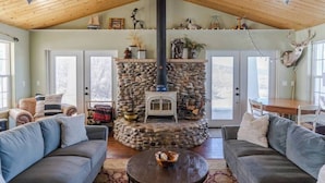 A cozy living room with a stone fireplace, wooden ceiling, and comfortable seating.