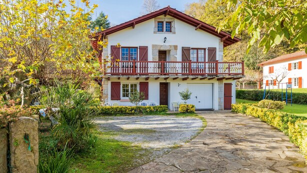 Een twee verdiepingen tellend huis met een balkon, een oprit van stenen en een tuin.