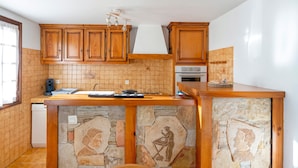 Een keuken met houten kastjes, een achterwand van steen en een inbouw eiland.